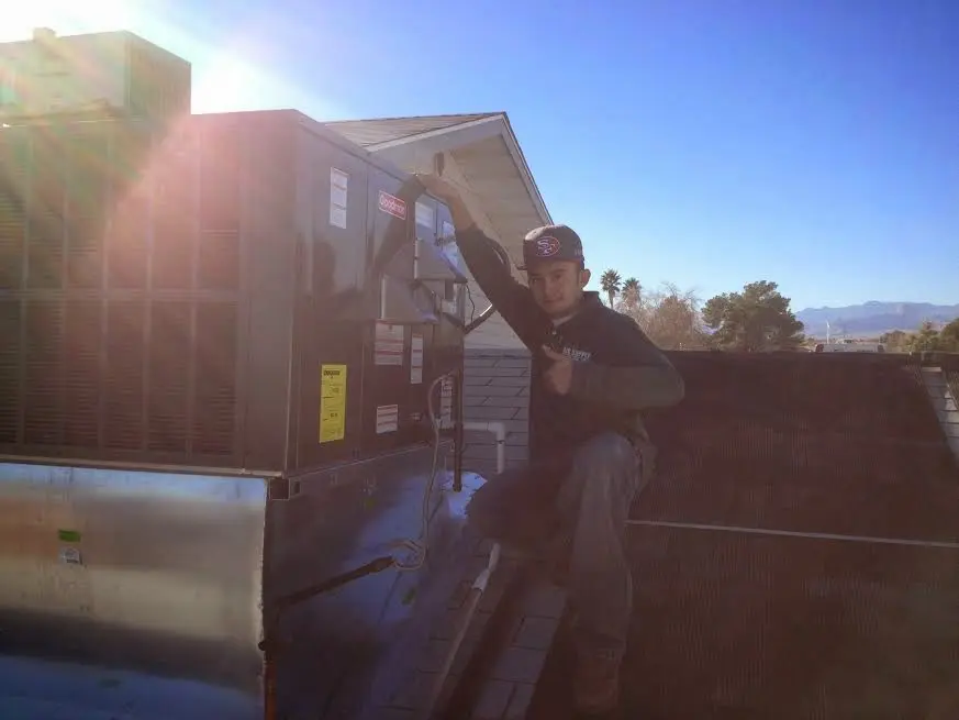 HVAC technician performing Air Duct Cleaning on a rooftop unit in Oak Point